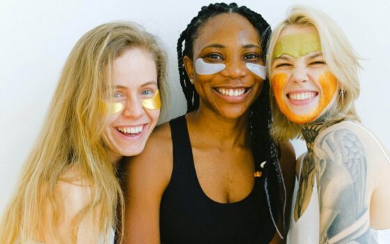 Photo par Anna Shvets: Trois jeunes femmes heureuses portant un masque de soins pour la peau