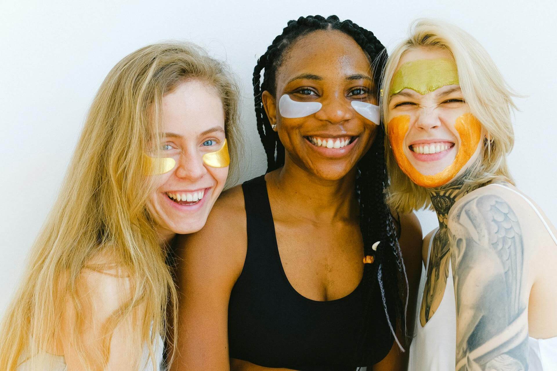 Photo par Anna Shvets: Trois jeunes femmes heureuses portant un masque de soins pour la peau